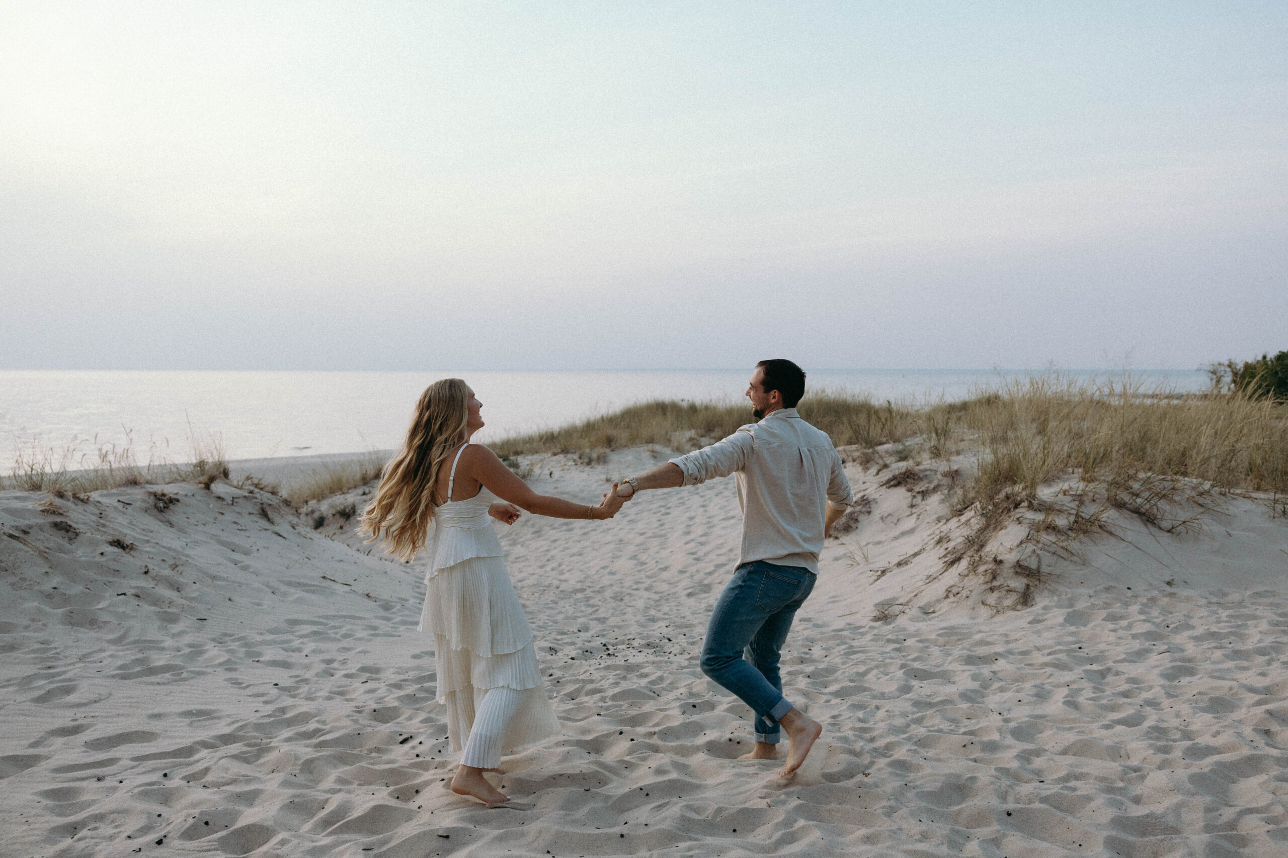 A man and woman playing and relaxing together at the beach, enjoying the sunset and the serene ocean view.