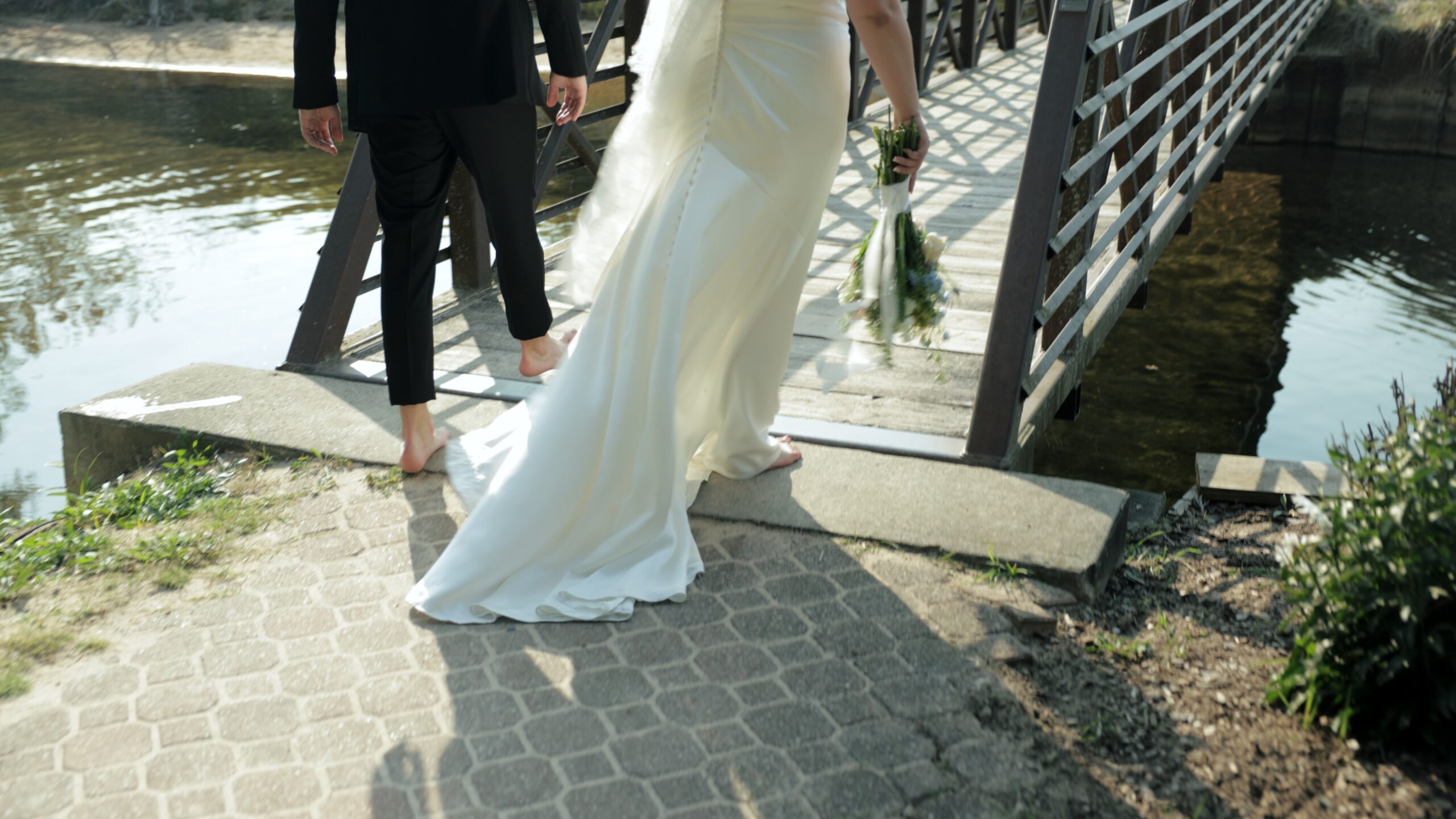 A bride and groom stroll hand in hand across a picturesque bridge with lots of joy, on their wedding day.