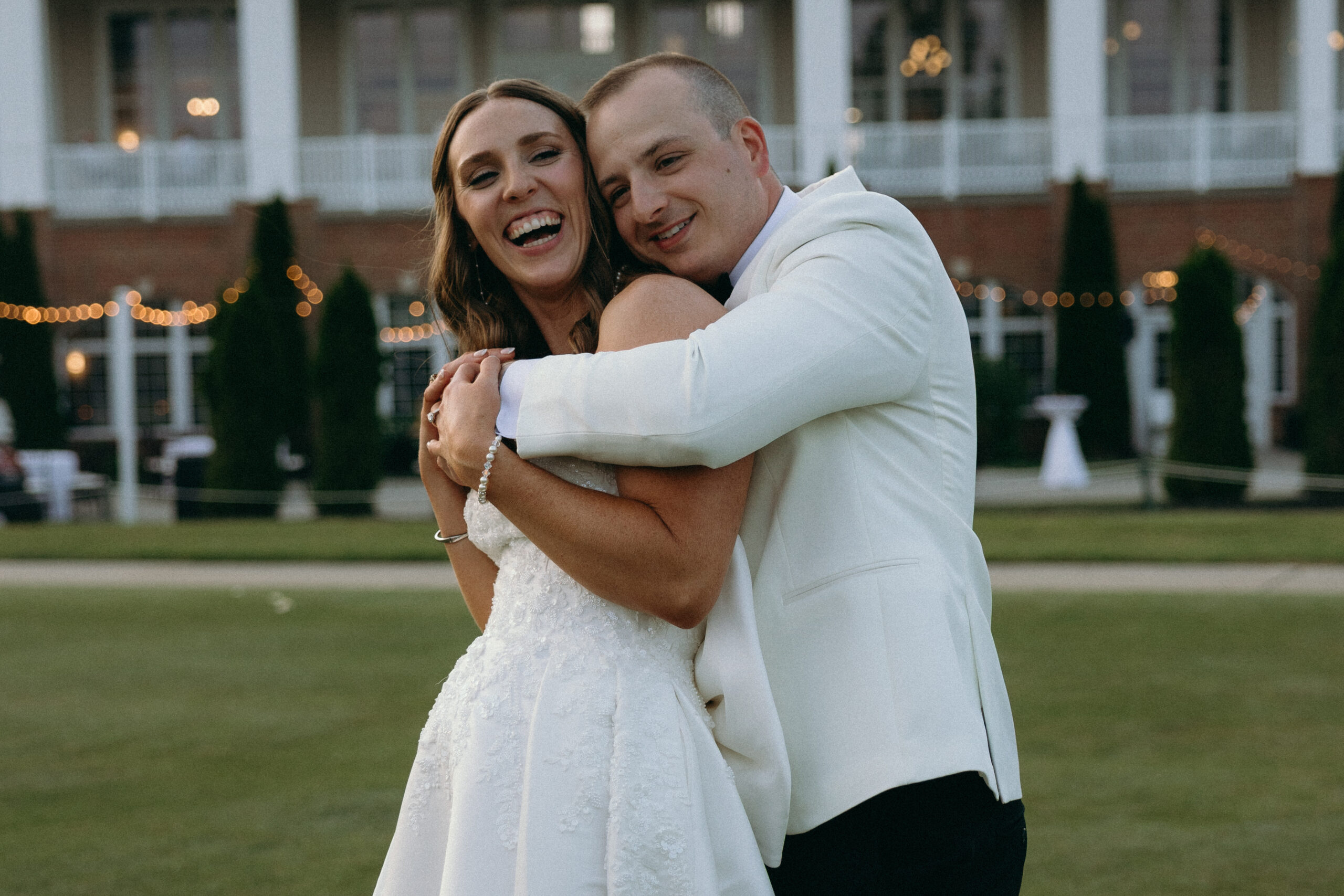 bride and groom embrace in front of their reception venue on their wedding day