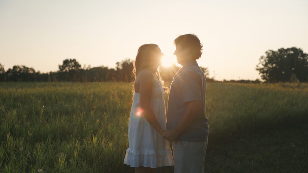 In a vibrant field, a woman and man lovingly hug each other, capturing a moment of affection and connection between them.   